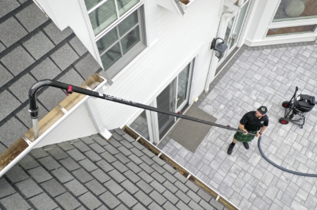 A Men In Kilts technician achieving a deeper gutter clean by using a water-fed pole. 