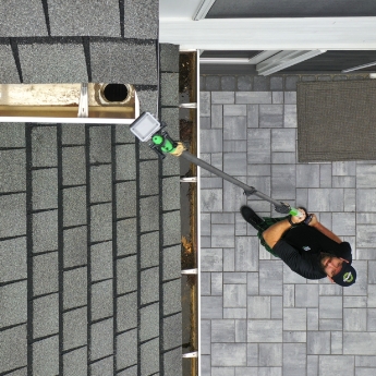 A Men In Kilts technician using a gutter inspection camera to see the highest places.